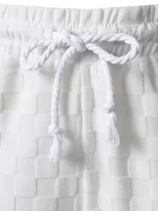 Close-up detail of white men's shorts with checkerboard jacquard fabric and rope drawstring