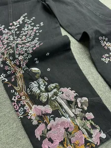 Dettaglio macro del ricamo floreale con fiori di ciliegio e cavaliere su jeans scuri