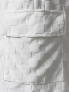 Macro view of white checkerboard jacquard fabric and pocket detail on casual shorts