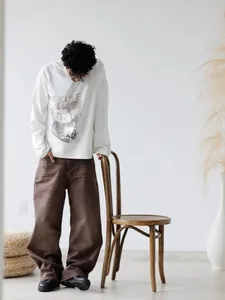 Model wearing loose-fit wide-leg brown denim trousers in a minimalist studio setting
