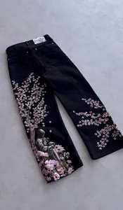 Dettaglio del ricamo Vescartes con fiori e cavaliere su jeans neri a gamba dritta