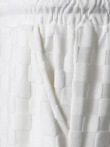 Macro detail of white checkerboard jacquard texture and functional pocket on men's shorts