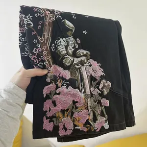 Dettaglio ravvicinato del ricamo di cavaliere e fiori su jeans in denim nero