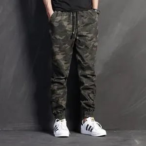 Men's dark camouflage cargo jogger pants styled with white sneakers in a full length view