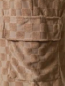 Macro detail of men's tan checkerboard jacquard shorts showing fabric texture and pocket