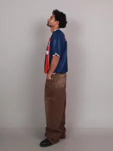Side profile detail of loose wide-leg washed brown denim pants with baggy streetwear fit