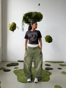 Model wearing matcha green wide-leg washed gradient denim pants in a creative studio