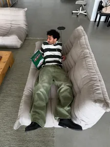 Model wearing matcha green wide-leg jeans with a washed gradient on a beige sofa