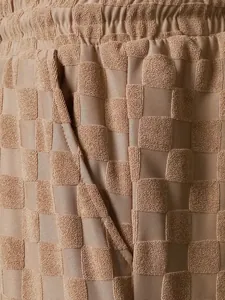 Detail view of men's casual shorts showing checkered jacquard texture and side pocket.