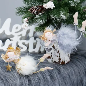 Two cute plush Christmas angel ornaments with crowns hanging on a tree branch