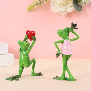 Romantisches Paar aus grünen Frosch-Harzfiguren mit rotem Herz für Valentinstag.