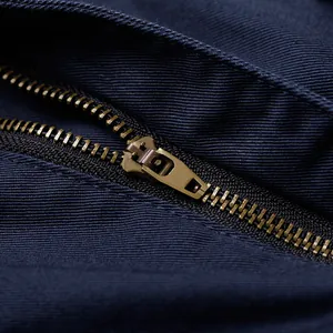 Close-up of durable antique brass metal zipper on dark navy blue men's cargo pants