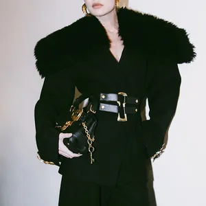 Detail of elegant black blazer featuring a large detachable fur collar and waist belt