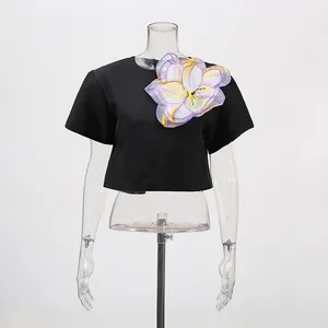 Detalle de top corto negro con gran aplique floral en 3D sobre maniquí transparente