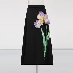 Detalle de falda negra de corte en A con un elegante aplique de flor 3D en violeta