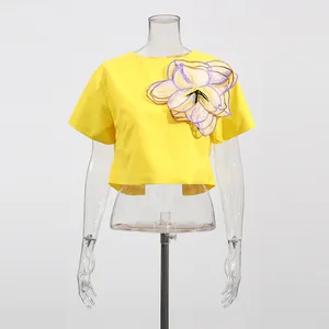 Detalle de top corto amarillo de manga corta con gran adorno de flor 3D en organza