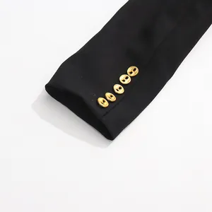 Detail of a black blazer sleeve featuring decorative vintage gold keyhole-shaped buttons.