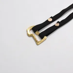 Close-up detail of a black elastic belt with a hammered golden metal buckle for blazers