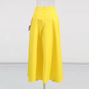 Vista posterior de una falda larga de línea A en color amarillo vibrante con talle alto.