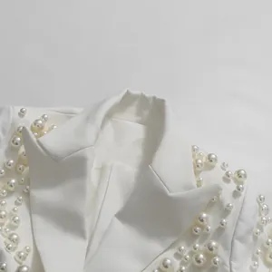 Vista dettagliata delle squisite decorazioni in perle bianche su rever e spalle del blazer