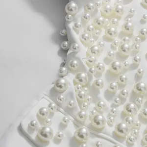 Vista macro dei delicati ricami di perle bianche su un top bianco alla moda di tendenza