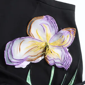 Primer plano del aplique floral bordado en 3D en la elegante falda negra línea A de estilo francés