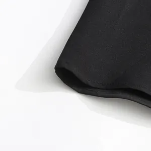 Primer plano del dobladillo de tela negra con costuras de precisión y textura.