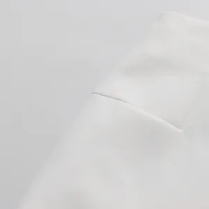 Dettaglio ravvicinato della trama del tessuto bianco e delle cuciture di un completo gonna