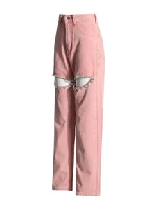 Close-up detail of pink high-waisted denim pants with rhinestone-embellished knee cutouts