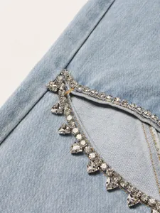 Close-up of rhinestone and triangle stud embellishment on light blue denim fabric