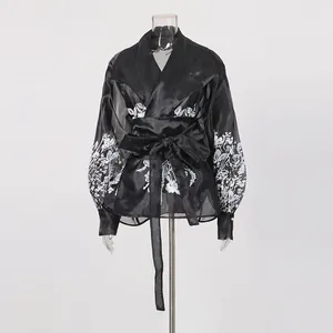 Detail of black floral palace lantern sleeve blouse with tie waist and lapel