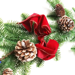 Guirlande de Noël avec aiguilles de pin givrées, pommes de pin et ruban de velours rouge