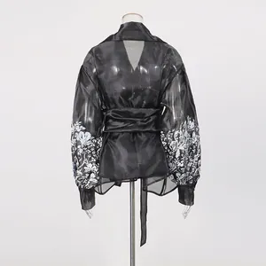 Detailed back view of a black sheer lantern sleeve blouse with white floral embroidery.