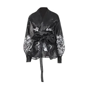 Detailed view of black sheer palace style blouse with white floral prints and tie-waist.