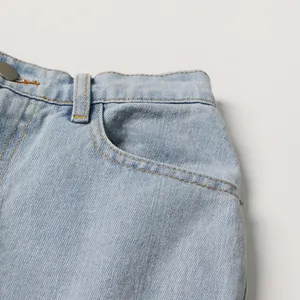 Detail of light blue high-waist denim jeans showing front pocket and waist stitching