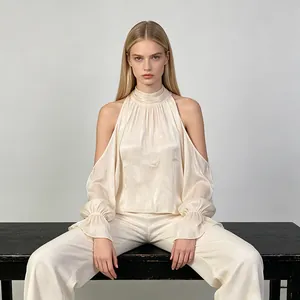 Elegante blusa color crema de cuello alto con hombros descubiertos y mangas acampanadas.