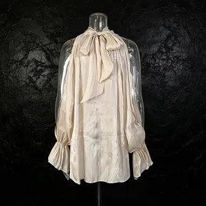 Detalle de blusa champagne con hombros descubiertos, elegante lazo y mangas acampanadas