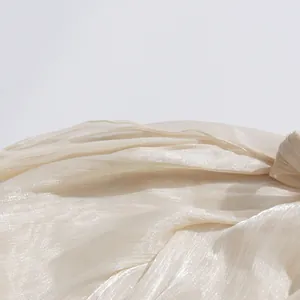 Primer plano de la textura de tela plisada champán brillante en blusa de mujer