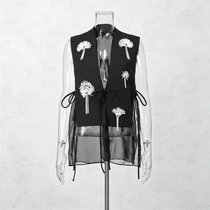 Vue détaillée du gilet en maille noire avec des fleurs à paillettes et des lacets