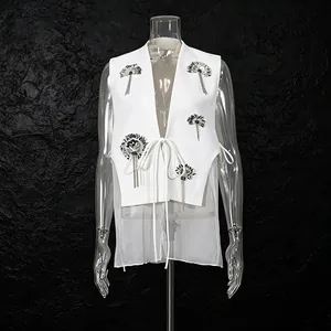 Vue détaillée d'un gilet blanc avec fleurs en paillettes et empiècement en résille
