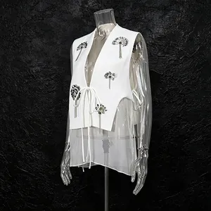 Vue détaillée du gilet blanc avec patchs floraux à paillettes et ourlet en mesh fin
