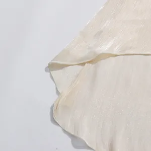 Primer plano de tela marfil brillante con textura plisada y detalle de dobladillo fino