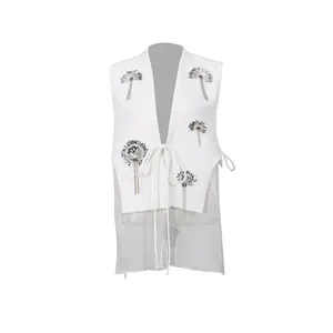 Vue détaillée du gilet blanc avec broderie florale en paillettes et empiècement en tulle