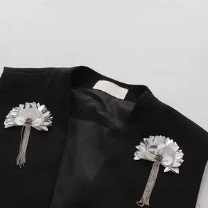 Vue détaillée d'un gilet noir orné de fleurs en paillettes argentées et de franges perlées.