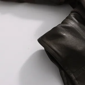 Macro close-up detail of pleated cuffs and leather texture on a vintage brown jacket