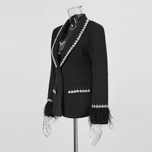 Detail showing the elegant rhinestone trim and luxurious feather cuffs on a black blazer.