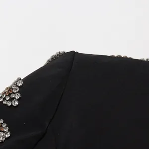 Gros plan de strass en cristal étincelants sur l'épaule d'un blazer noir pour femme.