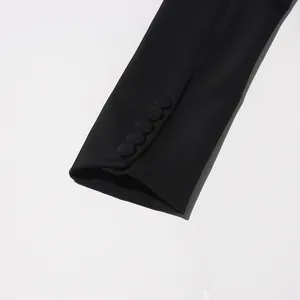 Gros plan sur la manche d'un blazer noir avec des boutons recouverts de tissu élégants