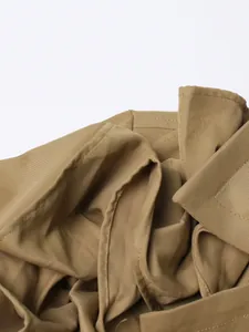 Close-up of khaki trench coat fabric showing fine twill texture and neat stitching