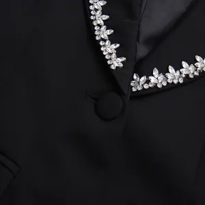 Detailed macro view of sparkling crystal rhinestones on a black suit jacket lapel.